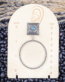 Outlaw Square Hoop Fashion Earrings on a ruler, on beans and wheat.