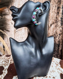 Canyon Bloom Fashion Hoop Earrings on a mannequin, sitting on cowhide, wood back drop. 