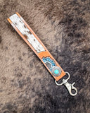 Far & Wide Hand-Tooled Key Fob displayed on cow hide.