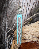 Teal Accent Hand-Tooled Strap Key Fob displayed on wheat, wood backdrop.