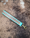 Teal Accent Hand-Tooled Strap Key Fob displayed on cowhide,