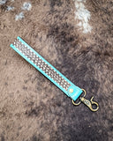 Teal Accent Hand-Tooled Strap Key Fob displayed on cow hide.