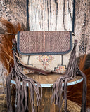 Front view of the Sandy Rosewood Hand-Tooled Bag displayed on a wood table, wood back drop.