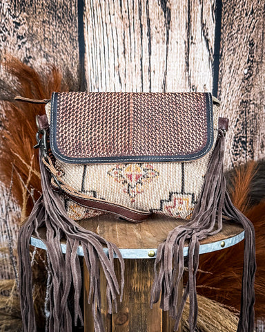 Front view of the Sandy Rosewood Hand-Tooled Bag displayed on a wood table, wood back drop.