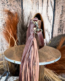 Side view of the Carved Blossoms Leather & Hairon Bag on a table, wood back drop.