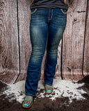 Front view of a girl modeling the Emberglow Embellished Bootcut Jeans, standing on cowhide.
