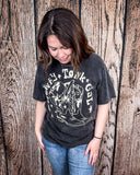 Girl modeling the Honky Tonk Gal Vintage Graphic Tee with a wood back drop.