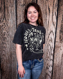 Girl modeling the Honky Tonk Gal Vintage Graphic Tee with a wood back drop.
