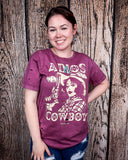 A girl modeling the Adios Cowboy Distressed Graphic Tee with a wood back drop.