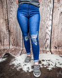 Front view of a girl wearing the Badlands Rip Skinny Jeans while standing on cowhide, wood back drop