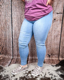 Side view of a girl modeling the High Noon Skinny Jeans on cowhide with a wood back drop.