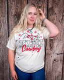 A girl modeling the Kick Rocks Cowboy Distressed Graphic Tee with a wood backdrop.