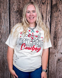 A girl modeling the Kick Rocks Cowboy Distressed Graphic Tee with a wood backdrop.