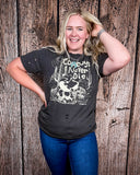 Model wearing the Cowboys Never Die Distressed Graphic Tee with a white back drop.