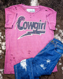 The Lightning Cowgirl Distressed Graphic Tee displayed on cowhide along with jeans.