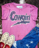 The Lightning Cowgirl Distressed Graphic Tee displayed on cowhide along with shoes and jeans.