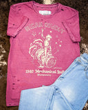 The Urban Cowboy Distressed Graphic Tee displayed on cowhide along with jeans.
