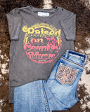 The Raised on 90's Country Distressed Graphic Tee displayed on cowhide along with jeans.