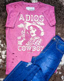 The Adios Cowboy Distressed Graphic Tee displayed on cowhide along with jeans.