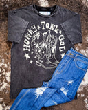 Honky Tonk Gal Vintage Graphic Tee displayed on cowhide along with jeans.