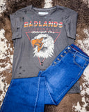 Badlands Motorcycle Club Graphic Tee displayed on cowhide along with jeans.
