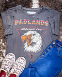 Badlands Motorcycle Club Graphic Tee displayed on cowhide along with shoes and jeans.