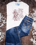The Still in The Saddle Graphic Tee displayed on cowhide along with jeans.