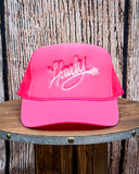 Front view of the Embroidered Rope Howdy Trucker Cap displayed on a wood table.