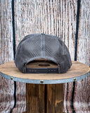 Back view of the Embroidered Rope Howdy Trucker Cap displayed on a wood table, wood backdrop.