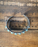 Top view of the Rayna Genuine Turquoise Bracelet sitting on a wood table.