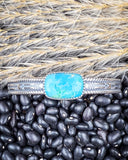 Zoom in of the Abha Genuine Turquoise Bracelet displayed on beans and wheat.