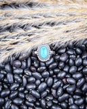 The Riley Adjustable Genuine Turquoise Ring displayed on beans and wheat.