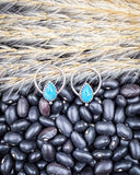 The Vale Genuine Turquoise Stud Earrings displayed on beans and wheat.