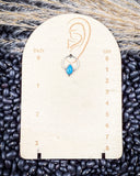 The Vale Genuine Turquoise Stud Earrings displayed on a ruler, sitting on beans and wheat.