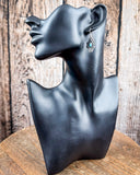 The Leif Genuine Turquoise Earrings on a mannequin, sitting on a wood table, wood backdrop.