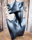 The Abeytu Genuine Turquoise Earrings on a mannequin, sitting on a wood table with a wood backdrop.