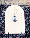 The Abeytu Genuine Turquoise Earrings displayed on a ruler, sitting on beans and wheat.
