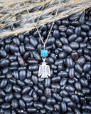 The Thunderbird Charm Genuine Turquoise Necklace displayed on beans and wheat.