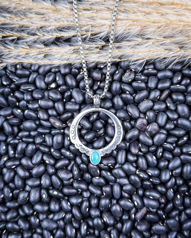 The Moongate Genuine Turquoise Necklace displayed on beans and wheat.