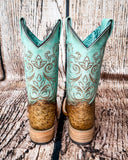 Back view of the Stormbird Ostrich Corral Boots in front of a wood backdrop.