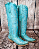 Side view of the Embroidered Sky Corral Boots with a wood backdrop.