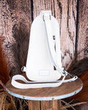 Back view of the Ridge Bloom Tooled Sling Bag - Ivory on a wood backdrop.