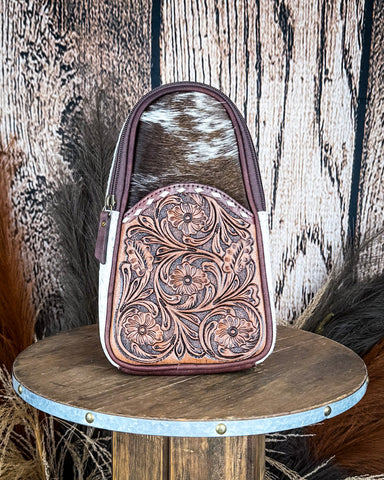 Front view of the Cimarron Tooled Sling Bag on a wood backdrop.