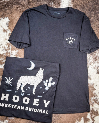 The Coyote Hooey T-Shirt displayed on cowhide, showing graphics on the front and back.