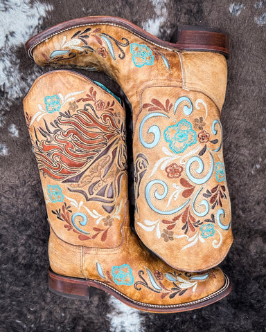The Sandstone Stallion Corral Boots displayed on cowhide.