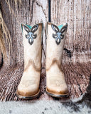 Front view of the Dustbowl Drifter Corral Boots with a wood backdrop.