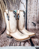 Side view of the Dustbowl Drifter Corral Boots with a wood backdrop.