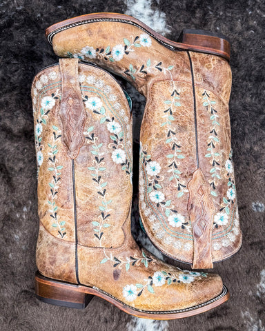 The Luminous Petal Corral Boots displayed on cowhide.