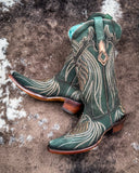 The Mystic Pine Corral Boots displayed on cowhide.