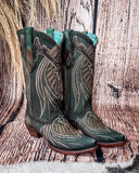 Side view of the Mystic Pine Corral Boots with a wood backdrop.